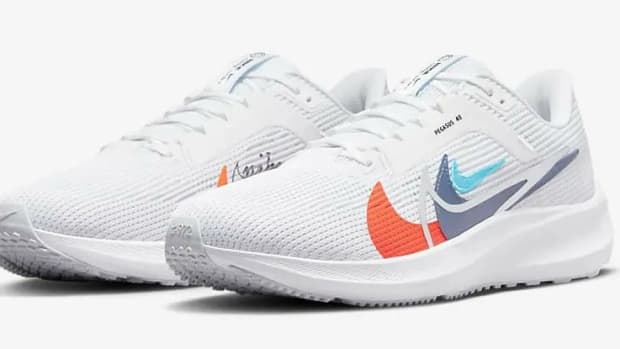 Side view of white and orange Nike running shoes.